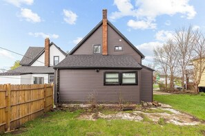 A residential house with a dark siding exterior, a brick chimney, and a small attached garage. - Spacious 5BR in vibrant area, walk to cafes, restaurants & galleries (Detroit)