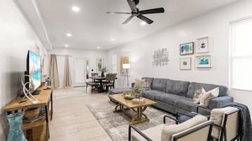A modern living room with a grey sofa, wooden coffee table, and a ceiling fan.