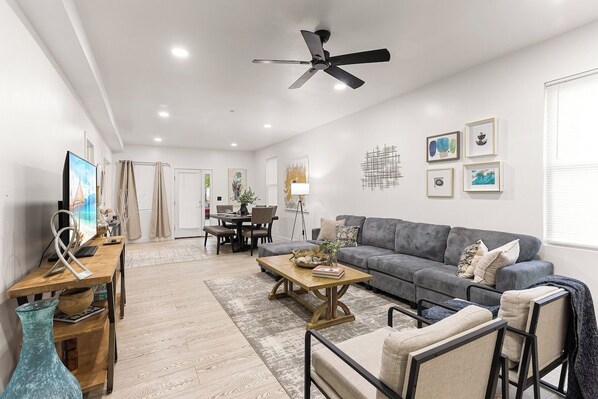 A modern living room with a grey sofa, wooden coffee table, and a ceiling fan.