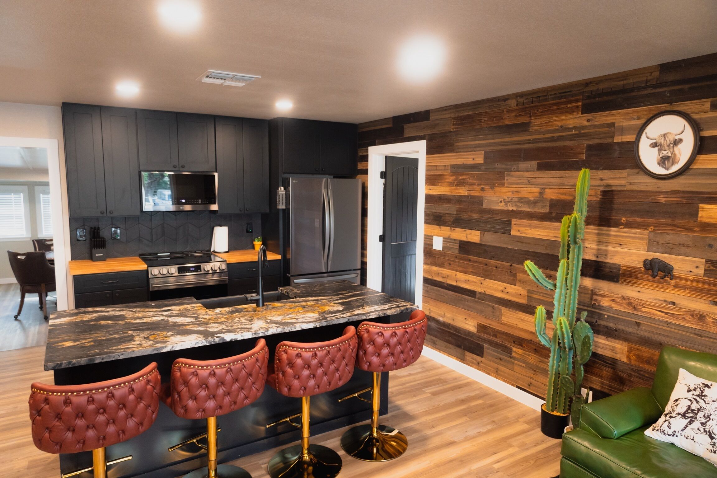 A modern kitchen with dark cabinetry, stainless steel appliances, and a marble island with bar stools.