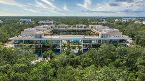 A modern hotel with multiple floors, a swimming pool, and surrounded by dense greenery. - Luxury Penthouse with Private Rooftop Pool (Tulum)