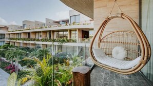 A modern hotel with a hanging chair, a balcony with plants, and a view of the building's exterior. - Luxury Penthouse with Private Rooftop Pool (Tulum)