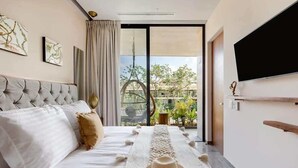 A bedroom with a bed, a TV, a balcony with a view, and a decorative table runner. - Luxury Penthouse with Private Rooftop Pool (Tulum)