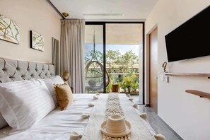A bedroom with a bed, a TV, a balcony with a view, and a decorative table runner. - Luxury Penthouse with Private Rooftop Pool (Tulum)