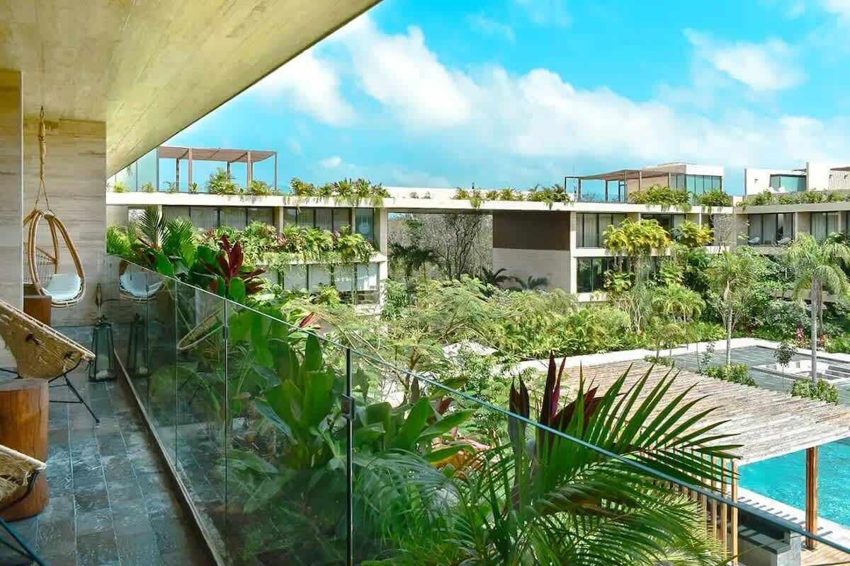 A modern building with multiple balconies, a glass railing, and a pool area.