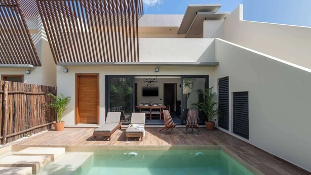 A modern house with a swimming pool, wooden deck, and a dining area with outdoor furniture. - Luxury Jungle Villa with Private Pool & Concierge (Tulum)