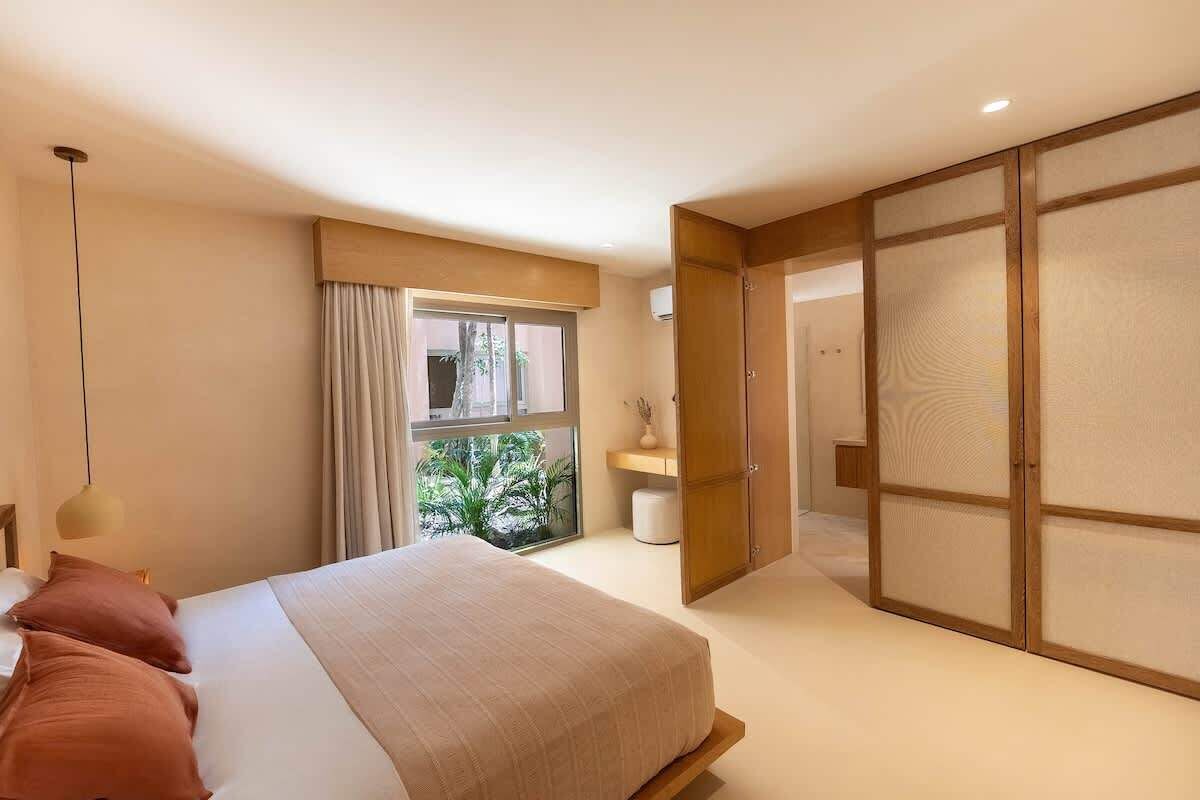 Een moderne slaapkamer met een bed, een raam met gordijnen, een nachtkastje en een schuifdeur.