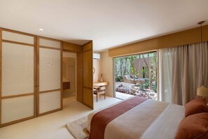 A bedroom with a bed, a desk, and a view of a garden. - Elegant 3BR in Aldea Zama with Private Pool (Tulum)