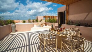 En takterrass med en pergola av trä, utomhusmöbler, en bubbelpool och utsikt över det omgivande landskapet.