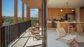 Ett modernt kök med en bardisk, en balkong med sittplatser och stora fönster som ger utsikt över omgivningen.