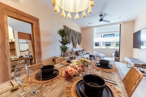 Ein Essbereich mit Holztisch, gedecktem Tisch für eine Mahlzeit, einem Deckenventilator und Blick ins Freie.