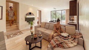 Ein modernes Wohnzimmer mit Sofa, Couchtisch und Essbereich, im Hintergrund eine Küche.