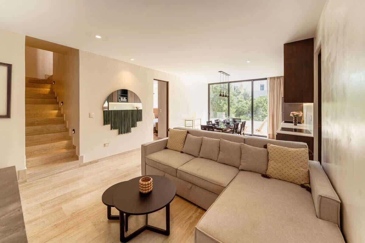A modern living room with a sectional sofa, a round coffee table, and a staircase leading to another level.