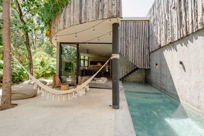 Ein moderner Außenbereich mit einer Hängematte, einem Pool und einer Treppe, die zu einem Innenbereich führt.