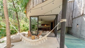 Een hangmat met stoelen, een zwembad en uitzicht op het interieur.