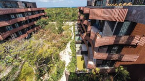 A modern building with multiple balconies, a pool, and a view of the ocean. - AMIRA Luxury 3BR PH with Rooftop and private pool (Tulum)