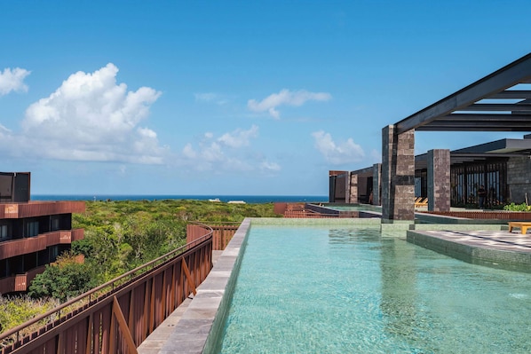 Ein Pool mit freiem Blick auf den Ozean, umgeben von modernen Gebäuden mit Balkonen.