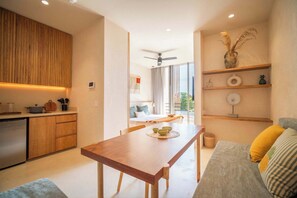 A modern kitchen with wooden cabinets and a dining area with a wooden table. - Chic Aldea Zama Condo with Pool & Parking (Tulum)