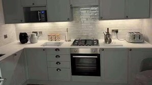 Uma cozinha moderna com armários cinza, micro-ondas, fogão a gás, torradeira e forno embutido.
