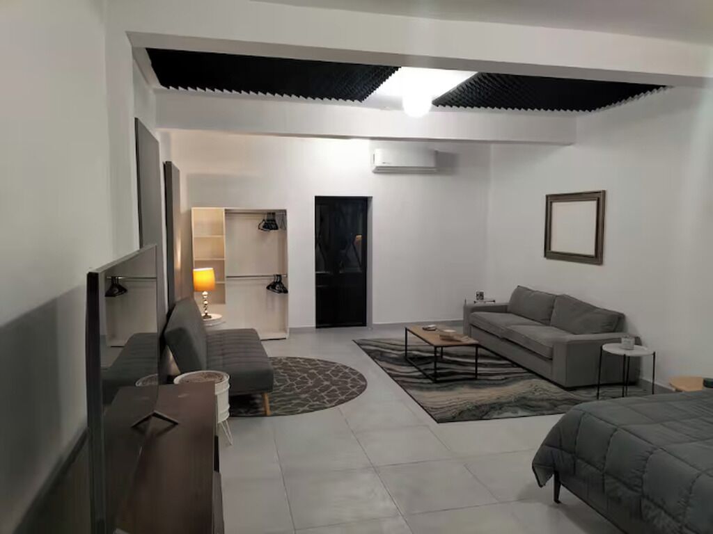 Une chambre moderne avec un canapé, un lit, une table basse et une lampe.