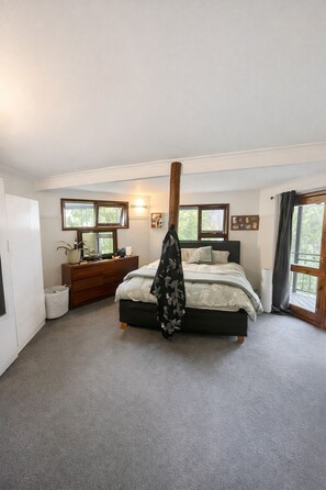 Een slaapkamer met een bed, een dressoir, nachtkastjes en een raam.
