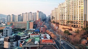 Un paysage urbain avec de hauts immeubles, un mélange de bâtiments résidentiels et commerciaux, et un ciel dégagé.