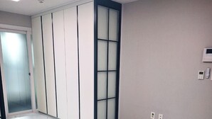 Un couloir doté d’un sol carrelé, d’une porte coulissante et d’un thermostat fixé au mur.