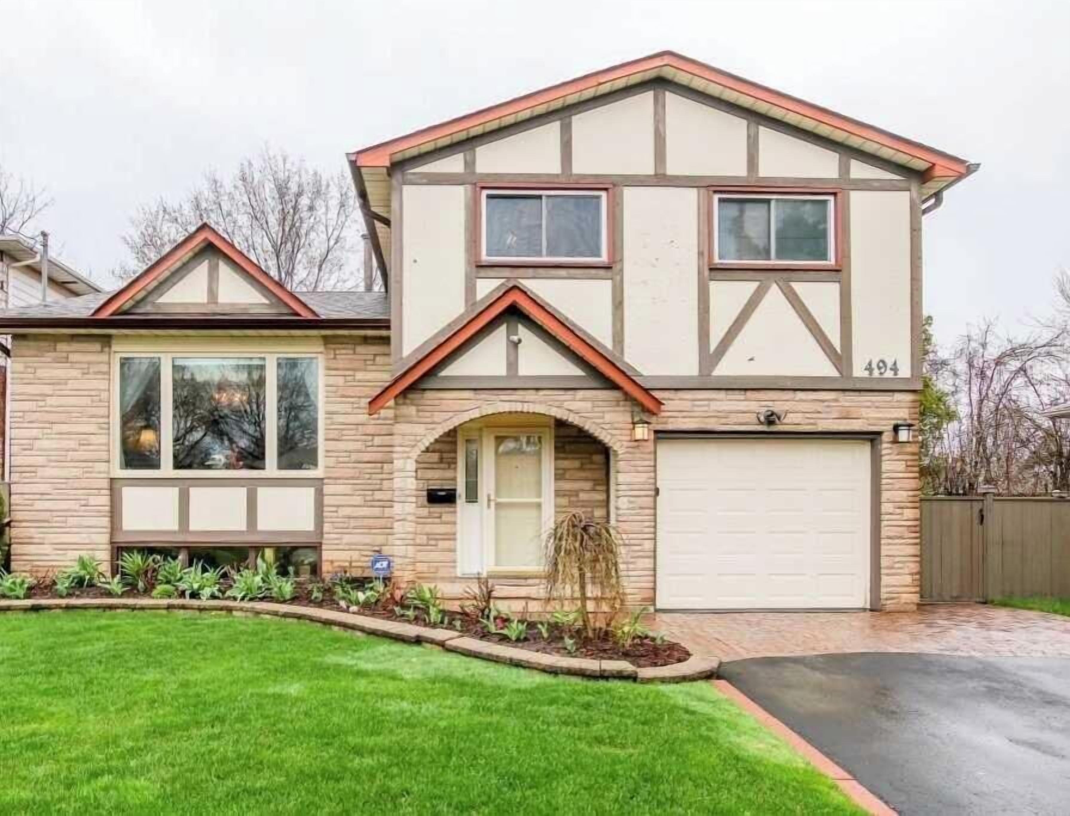 A two-story house with a garage, a front entrance with an arch, and a number '494' on the side.
