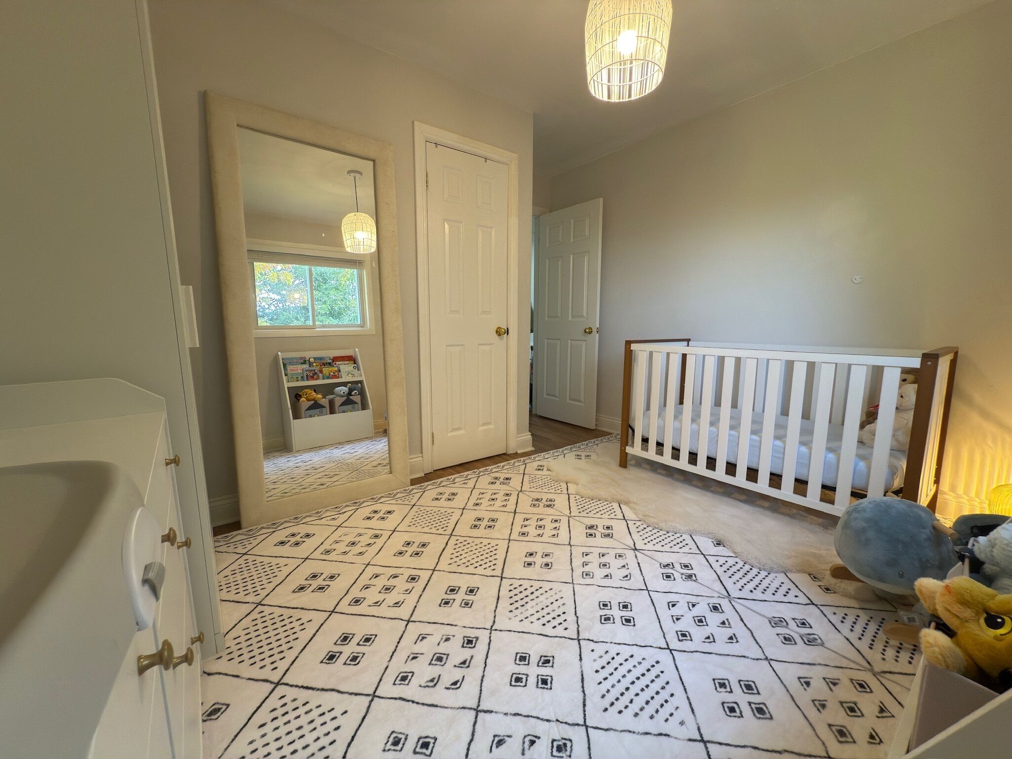 A baby room with a crib, a play area with toys, and a patterned floor.