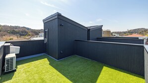 A rooftop with artificial grass, a modern building, and a clear sky. - Charm Roger luxury room Bridge (Kamakura)