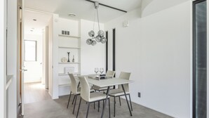 A modern dining area with a white table, six chairs, and a unique chandelier. - Charm Roger luxury room Bridge (Kamakura)