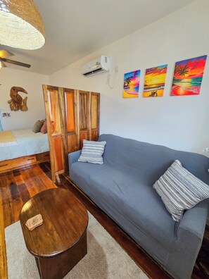 A living room with a grey sofa, wooden floor, a round coffee table, and a hanging light fixture.