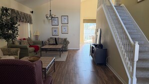 A living room with a sofa, armchair, coffee table, and a staircase. - Magical Disney Retreat w/Private Heated Pool/Hot Tub - Spacious 5-bedroom (Kissimmee)