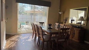A dining area with a table, chairs, a lamp, and a large mirror. - Magical Disney Retreat w/Private Heated Pool/Hot Tub - Spacious 5-bedroom (Kissimmee)