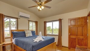 Una camera da letto con un letto in legno, una ventola a soffitto e ampie finestre.