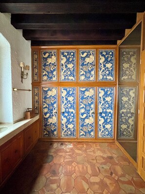 A bathroom with a tiled floor, a wooden bench, and a wall with decorative tiles. - Avicena Boutique Hotel - Cuernavaca (Cuernavaca)