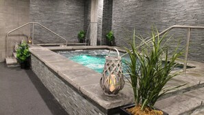 Ein Wellnessbereich mit Steinwand, Whirlpool und Laterne.