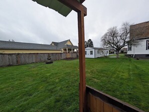 A backyard with a wooden deck, a small shed, and a house with a sloped roof.