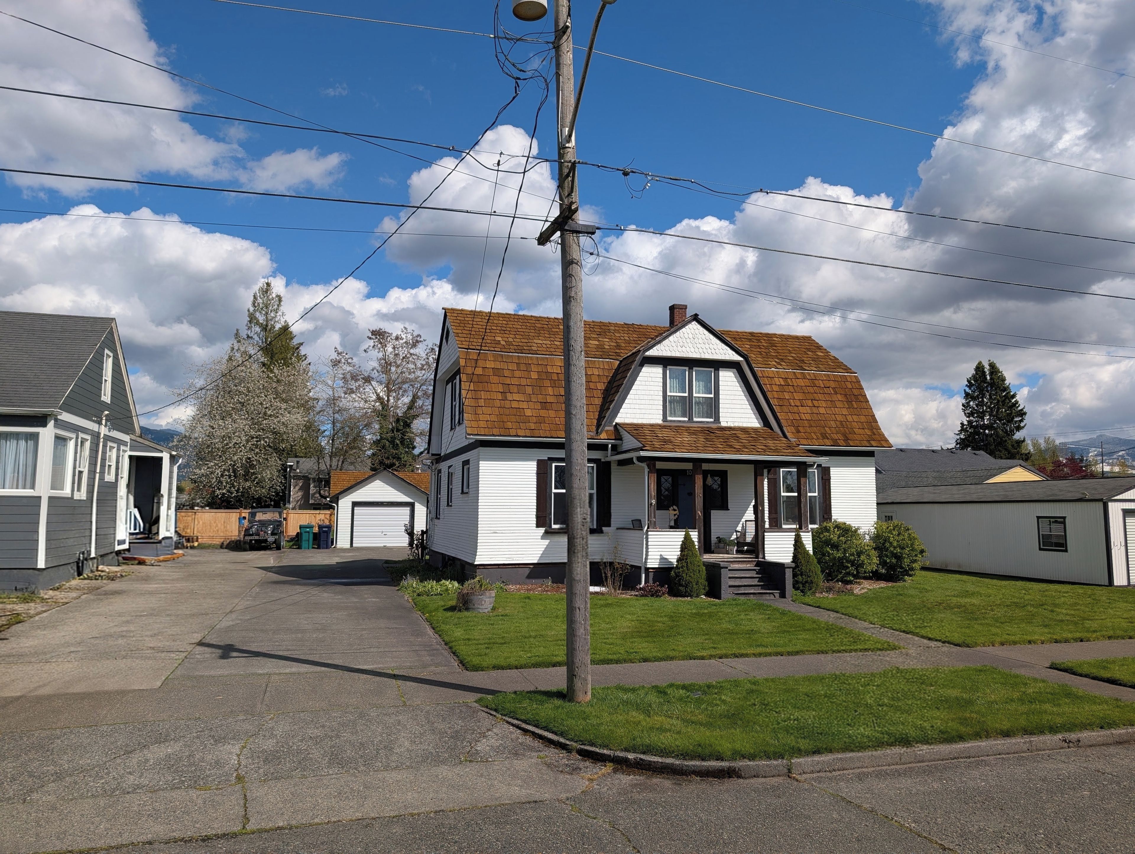 A residential street with houses, a clear sky, and a visible power line.