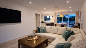 A modern living room with a sofa, coffee table, and a TV mounted on the wall.