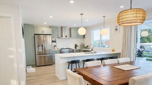 A modern kitchen with a central island, stainless steel appliances, and pendant lighting.