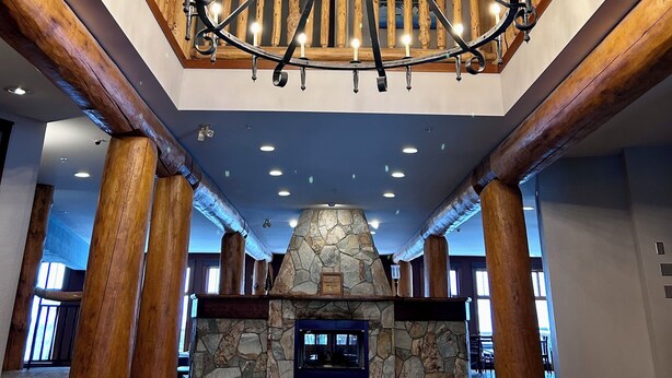 A grand lobby with a stone fireplace, wooden beams, and a chandelier. - Spectacular Ski-in/Ski-out Mountain Condo with A/C! (Fernie)