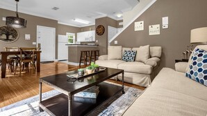 Uma sala de estar com sofá, mesa de centro e uma área de jantar com mesa e cadeiras.