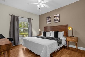 A bedroom with a large bed, a ceiling fan, two bedside tables with lamps, a window with curtains, and two wall-mounted pictures. - Cozy 4bdr House Gated Community Near Disney - 1105 (Kissimmee)