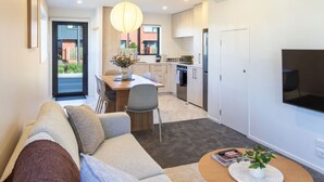 Un appartement moderne comprenant un salon, un coin repas, une cuisine et un téléviseur fixé au mur.