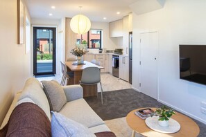 A modern apartment with a living room, dining area, kitchen, and a TV mounted on the wall. - Central Hereford St Stay Near Cafés & Transport (Christchurch)