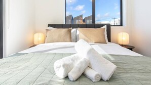 Une chambre d’hôtel avec un lit, des oreillers, une couette et deux lampes de chevet.