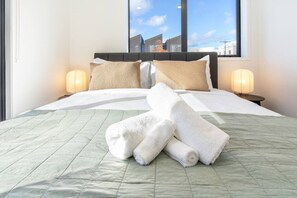 A hotel room with a bed, pillows, a quilt, and two bedside lamps. - Central Hereford St Stay Near Cafés & Transport (Christchurch)