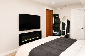 Ein Schlafzimmer mit Bett, Fernseher, Kamin, Kleiderschrank und Spiegel.