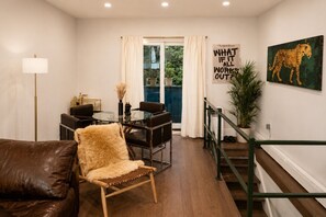 Ein modernes Wohnzimmer mit Glastisch, Ledersofa und einem Kunstwerk mit Leopardenmuster.